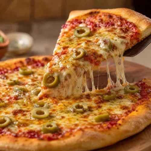 A hot pizza slice with melted cheese and sliced green olives being lifted from a fresh pizza.